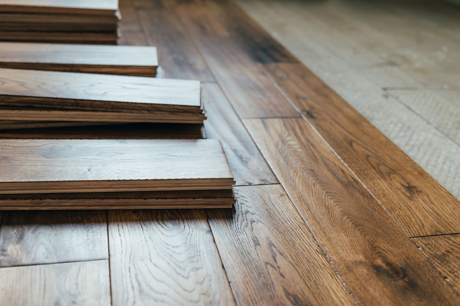 Hardwood floor planks being laid across a room